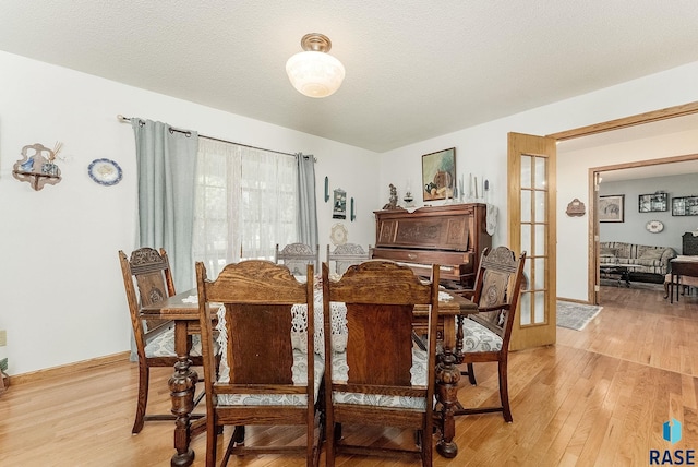 dining area with light wood-style flooring, french doors, and baseboards