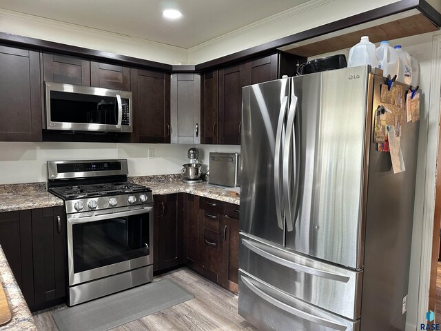 531 N Adams St, Salem, SD 57058 - kitchen with stainless steel appliances, light wood-style flooring, dark brown cabinets, crown molding, and light stone counters