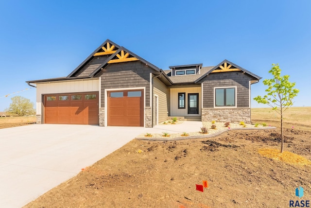 craftsman-style house with stone siding, an attached garage, and concrete driveway