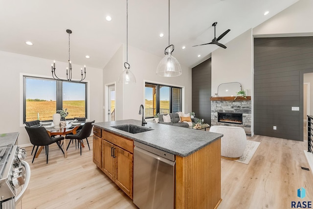 kitchen featuring appliances with stainless steel finishes, a sink, light wood finished floors, high vaulted ceiling, and an island with sink
