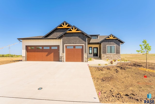 craftsman house with an attached garage, stone siding, and concrete driveway
