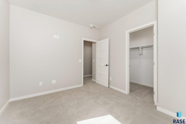unfurnished bedroom featuring carpet, a spacious closet, and baseboards
