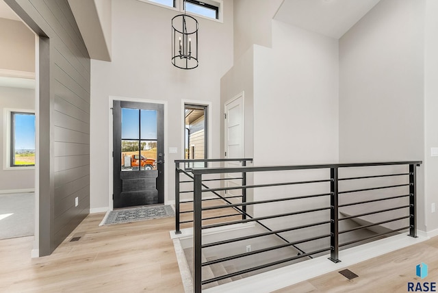 entryway with wood finished floors, baseboards, and a high ceiling
