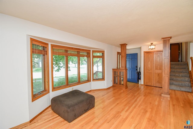 4600 S Harrington Ave, Sioux Falls, SD 57103 - living area featuring ornate columns, light wood-style flooring, baseboards, and stairs