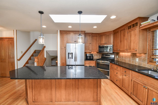 4600 S Harrington Ave, Sioux Falls, SD 57103 - kitchen featuring stainless steel appliances, a skylight, a sink, light wood-style flooring, and brown cabinetry