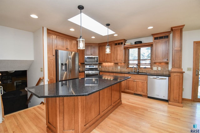 4600 S Harrington Ave, Sioux Falls, SD 57103 - kitchen with stainless steel appliances, a sink, light wood-style floors, brown cabinetry, and backsplash