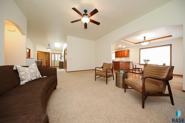 5223 E Pop Fly Pl, Sioux Falls, SD 57110 - living room with arched walkways, ceiling fan, baseboards, and light colored carpet