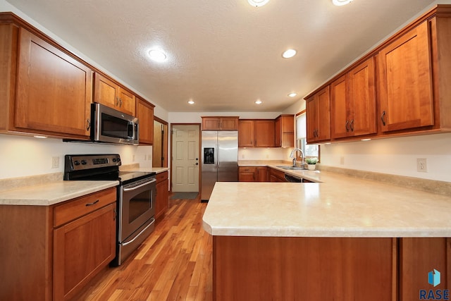 5223 E Pop Fly Pl, Sioux Falls, SD 57110 - kitchen featuring appliances with stainless steel finishes, light countertops, brown cabinetry, a peninsula, and recessed lighting