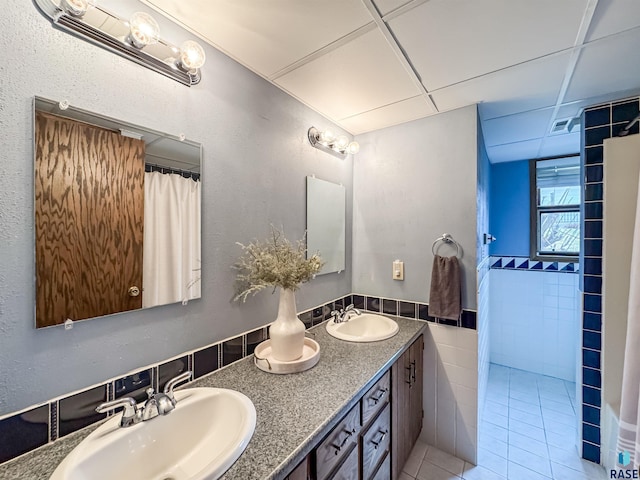 120 S Yellowstone Dr, Brandon, SD 57005 - bathroom with tile walls, tile patterned floors, a drop ceiling, double vanity, and wainscoting