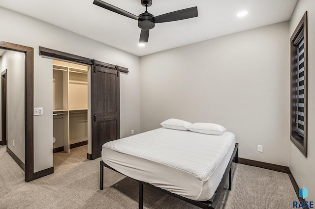 8209 E Ladyslipper Cir, Sioux Falls, SD 57110 - bedroom with light carpet, a barn door, baseboards, a walk in closet, and ceiling fan