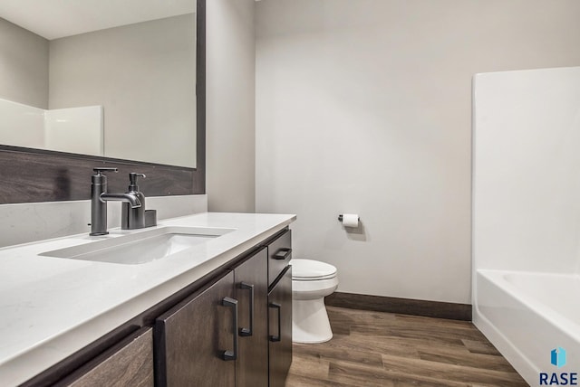 8209 E Ladyslipper Cir, Sioux Falls, SD 57110 - bathroom featuring toilet, wood finished floors, baseboards, vanity, and a tub to relax in