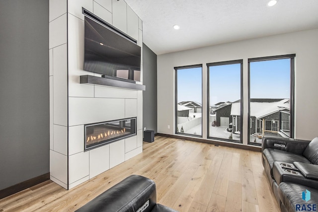 8209 E Ladyslipper Cir, Sioux Falls, SD 57110 - living area featuring light wood-type flooring, recessed lighting, a glass covered fireplace, and baseboards