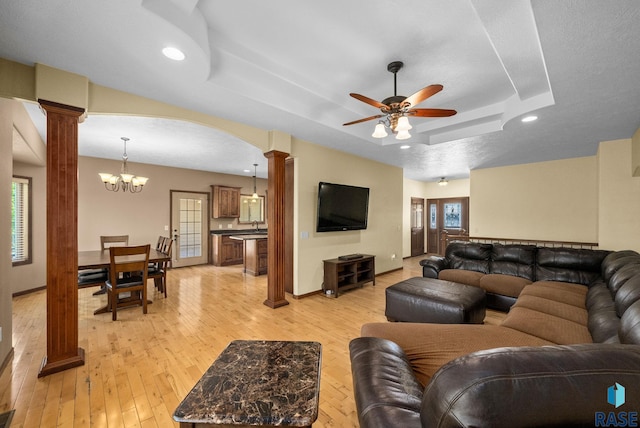 2305 N Ivy Rd, Tea, SD 57064 - living room featuring ornate columns, a tray ceiling, light wood-style floors, a ceiling fan, and a chandelier