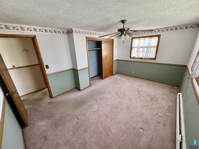 unfurnished bedroom featuring a closet, carpet floors, a textured ceiling, a ceiling fan, and baseboards