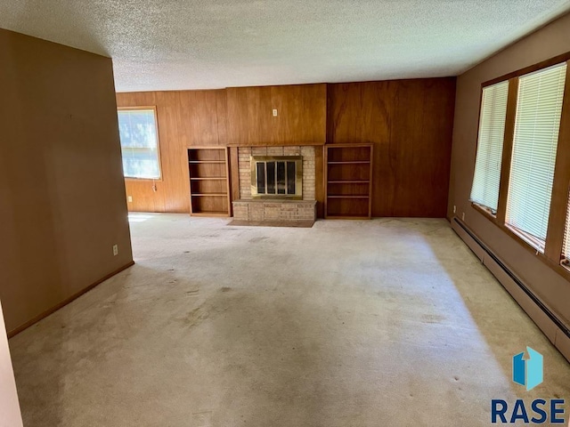 unfurnished living room featuring a textured ceiling, a baseboard radiator, wood walls, light carpet, and a fireplace