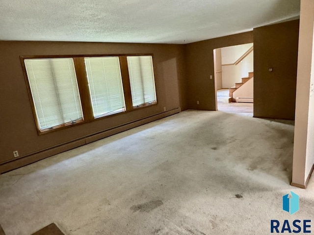 unfurnished room featuring stairway, carpet flooring, baseboard heating, and a textured ceiling