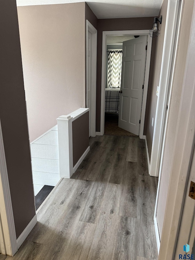 hallway featuring wood finished floors and baseboards