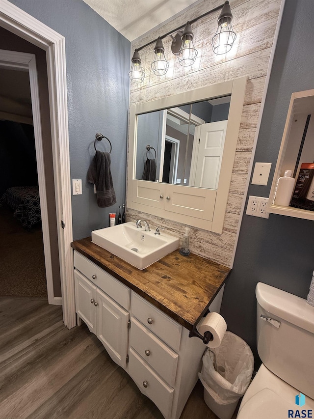 bathroom featuring wood finished floors, toilet, and vanity