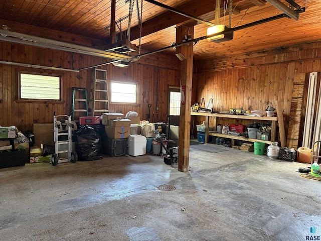 garage with wood walls, a garage door opener, and a workshop area