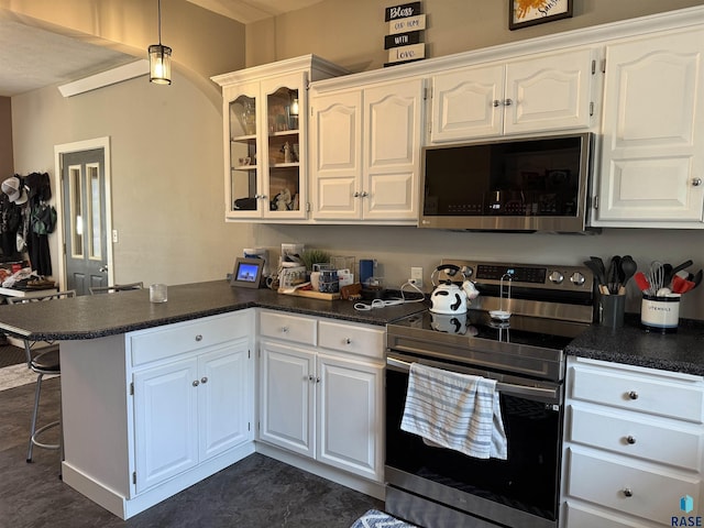 kitchen with appliances with stainless steel finishes, a peninsula, dark countertops, and white cabinets