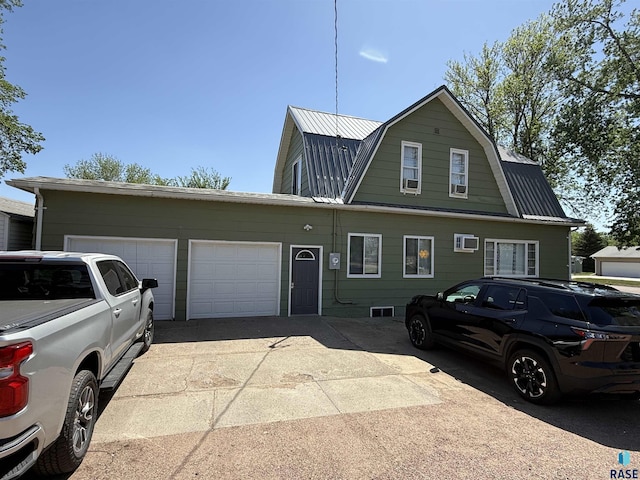 view of front facade featuring a gambrel roof, metal roof, an attached garage, and driveway
