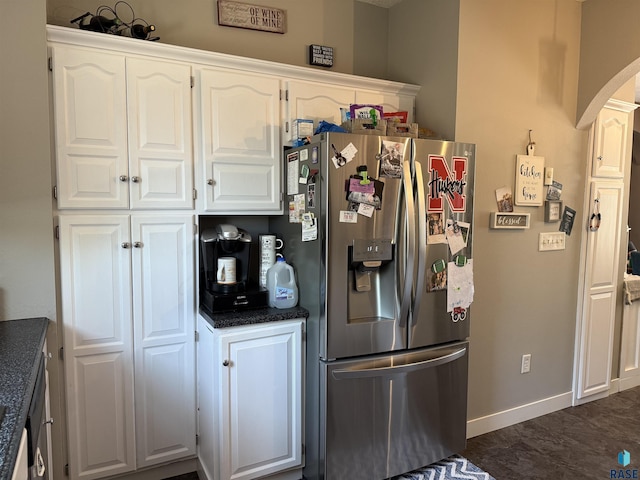 kitchen with stainless steel fridge with ice dispenser, arched walkways, white cabinetry, dark countertops, and baseboards
