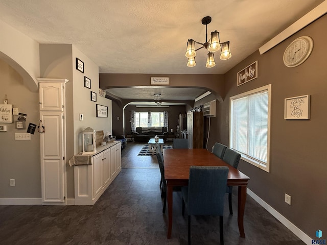 dining area with arched walkways, a chandelier, baseboards, a textured ceiling, and ceiling fan