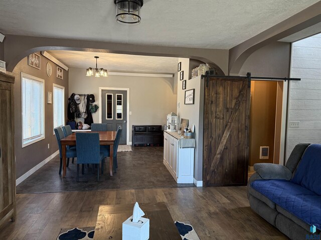 dining area featuring arched walkways, dark wood-type flooring, a barn door, baseboards, and a chandelier