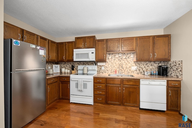 3600 S Gateway Blvd Unit 201, Sioux Falls, SD 57106 - kitchen featuring white appliances, a sink, wood finished floors, brown cabinets, and decorative backsplash
