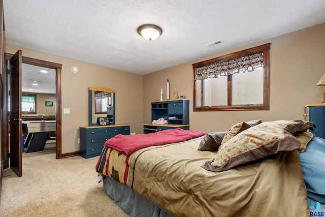 bedroom with light colored carpet and a textured ceiling