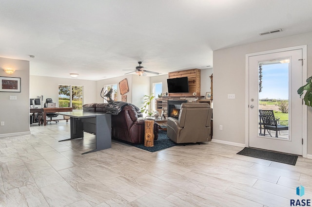 46370 237th St, Wentworth, SD 57075 - living area featuring a glass covered fireplace, a ceiling fan, light marble finish floors, baseboards, and a desk