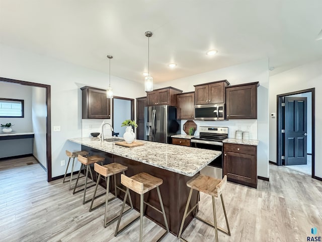 8612 W Dalton St, Sioux Falls, SD 57106 - kitchen featuring appliances with stainless steel finishes, a breakfast bar area, dark brown cabinets, and light wood-style flooring