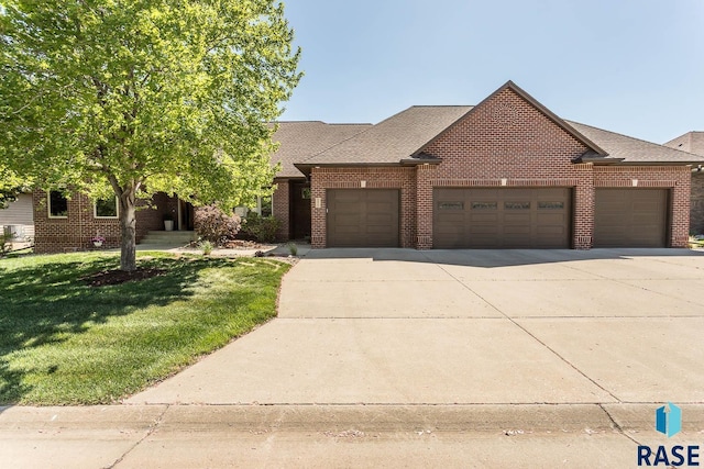 view of front of home with an attached garage, a front yard, brick siding, and driveway