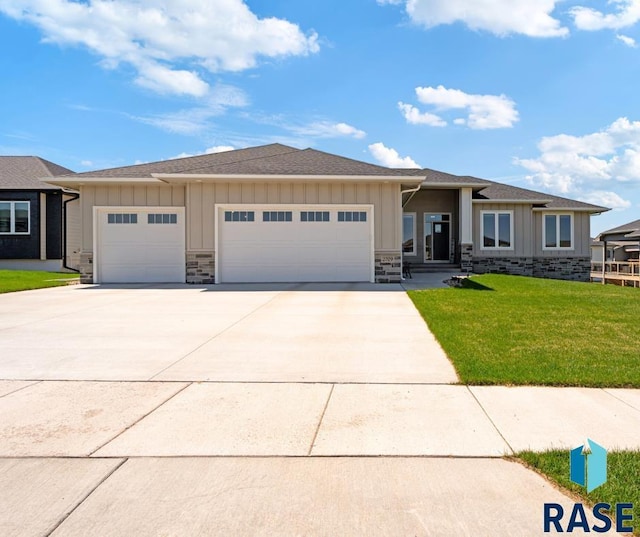 prairie-style home featuring board and batten siding, an attached garage, concrete driveway, and a front lawn