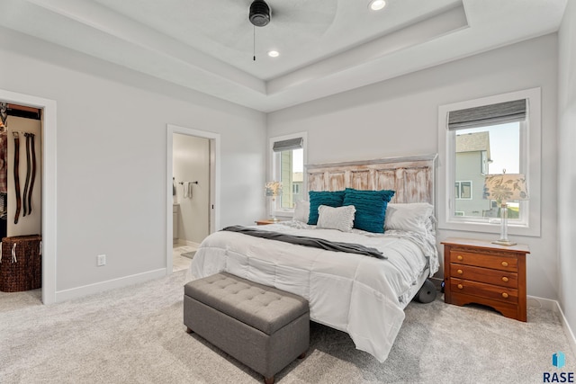 carpeted bedroom featuring baseboards, a tray ceiling, recessed lighting, a spacious closet, and connected bathroom