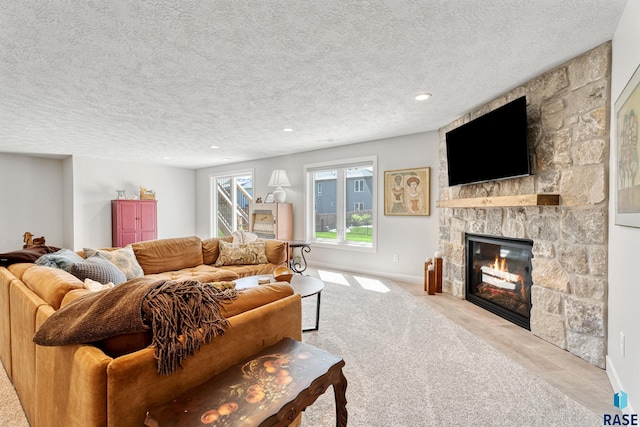living room featuring a stone fireplace, a textured ceiling, recessed lighting, baseboards, and carpet floors