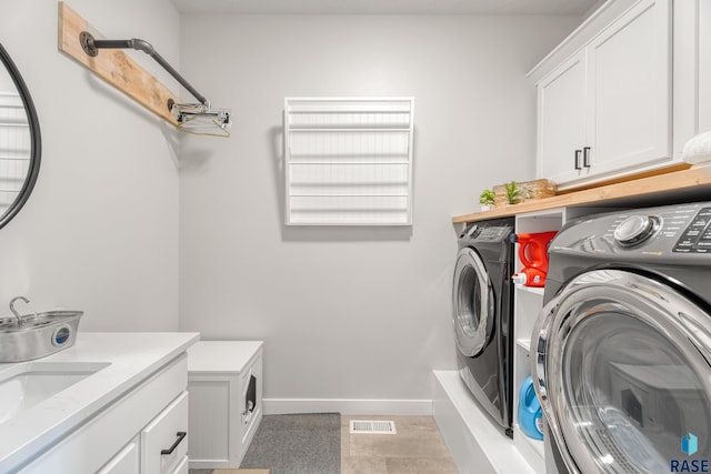 clothes washing area with washer and clothes dryer, cabinet space, and baseboards