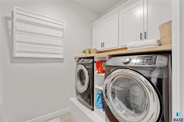 washroom featuring washer and dryer, cabinet space, and baseboards
