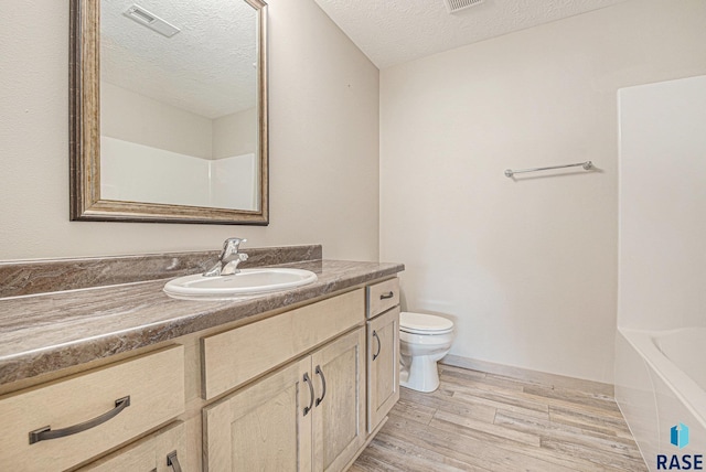 2629 S Richie Dr, Sioux Falls, SD 57106 - full bathroom with toilet, wood finished floors, a textured ceiling, vanity, and a bath