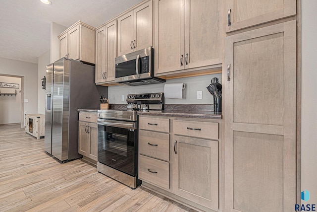 2629 S Richie Dr, Sioux Falls, SD 57106 - kitchen with stainless steel appliances, light wood-style flooring, dark countertops, and light brown cabinetry