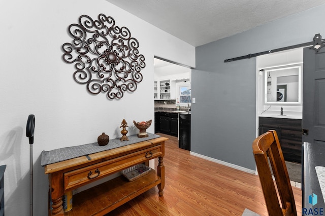 dining space featuring a barn door, light wood finished floors, and baseboards