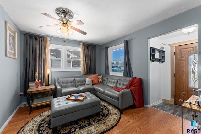 living room with ceiling fan, baseboards, and wood finished floors