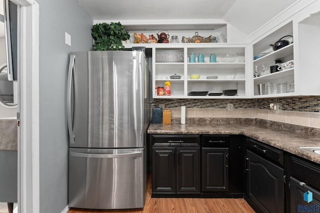 kitchen featuring freestanding refrigerator, open shelves, light wood finished floors, and tasteful backsplash