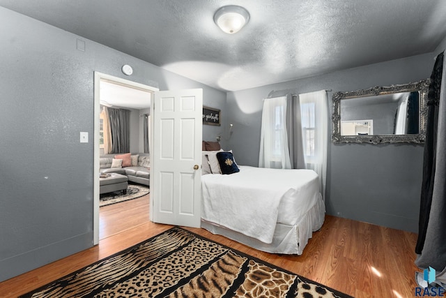 bedroom with wood finished floors, a textured ceiling, and a textured wall
