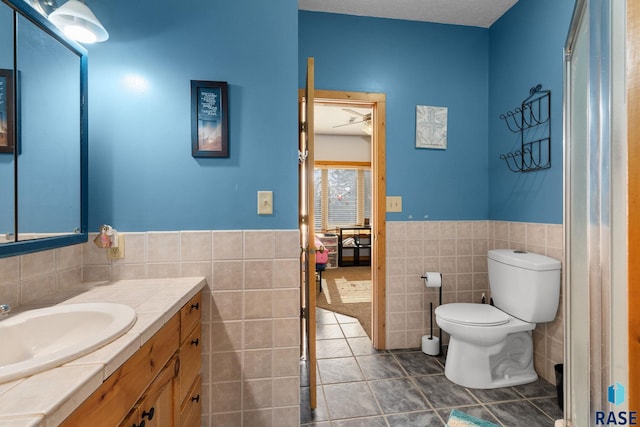 31780 476th Ave, Elk Point, SD 57025 - bathroom featuring tile walls, toilet, a wainscoted wall, vanity, and tile patterned flooring