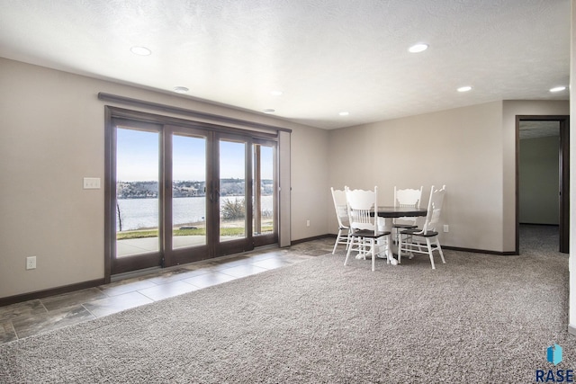 carpeted dining space with french doors, baseboards, a water view, and recessed lighting