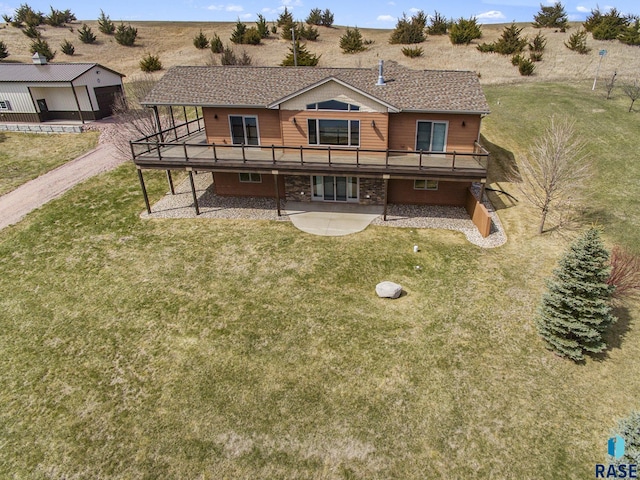 back of property with a yard, a wooden deck, and a patio