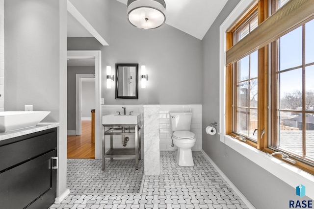 705 E 21st St, Sioux Falls, SD 57105 - bathroom with lofted ceiling, tile walls, healthy amount of natural light, toilet, and wainscoting