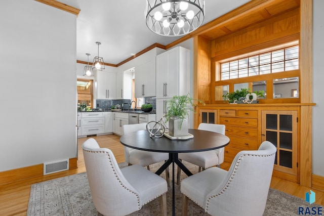 705 E 21st St, Sioux Falls, SD 57105 - dining space with crown molding, a chandelier, light wood-type flooring, and baseboards