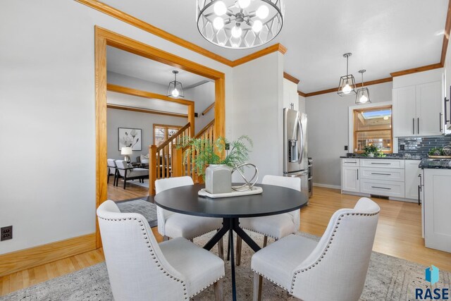 705 E 21st St, Sioux Falls, SD 57105 - dining space featuring stairway, light wood-type flooring, a chandelier, ornamental molding, and baseboards